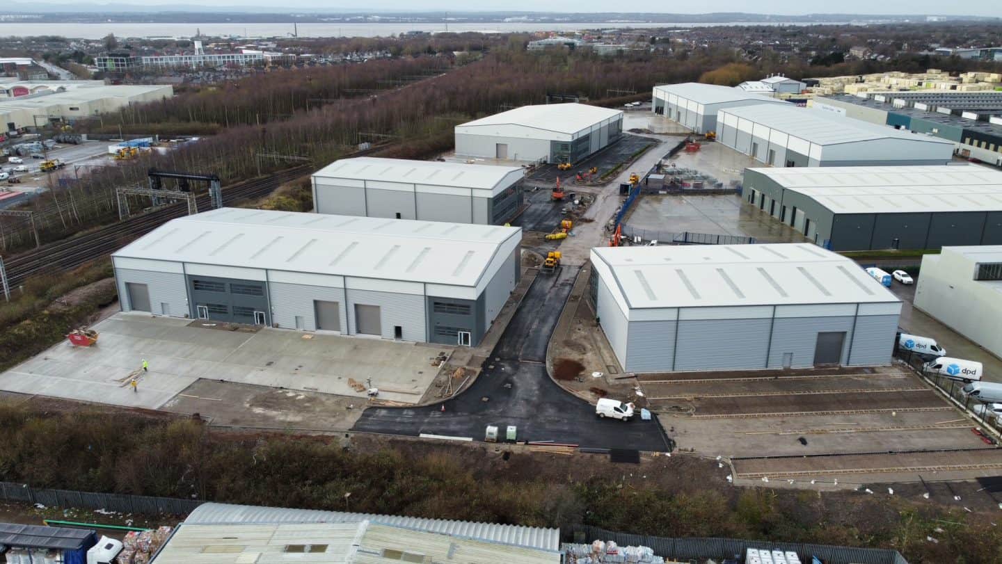 Aerial view of nearly-complete industrial units on a business park with a river and city in the background